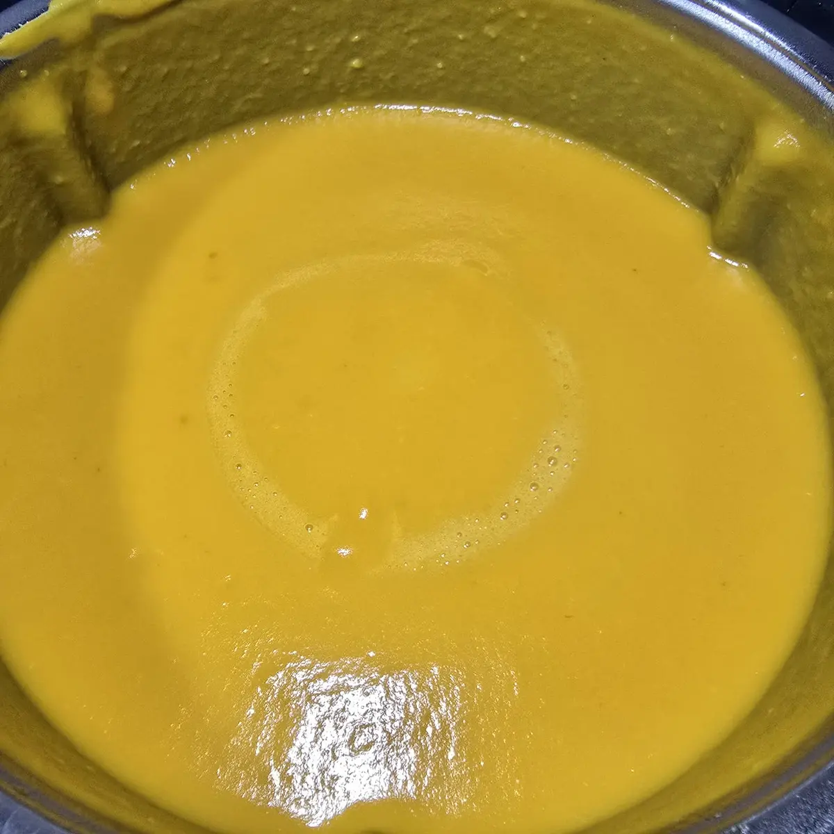 Gładka pomarańczowa zupa krem z dyni po zmiksowaniu w naczyniu Thermomix
