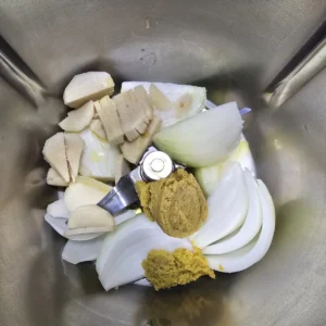 Cebula, czosnek i świeży imbir w naczyniu Thermomix przed rozdrobnieniem