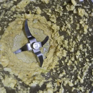 Rozdrobniona cebula, czosnek i imbir na dnie naczynia miksującego Thermomix